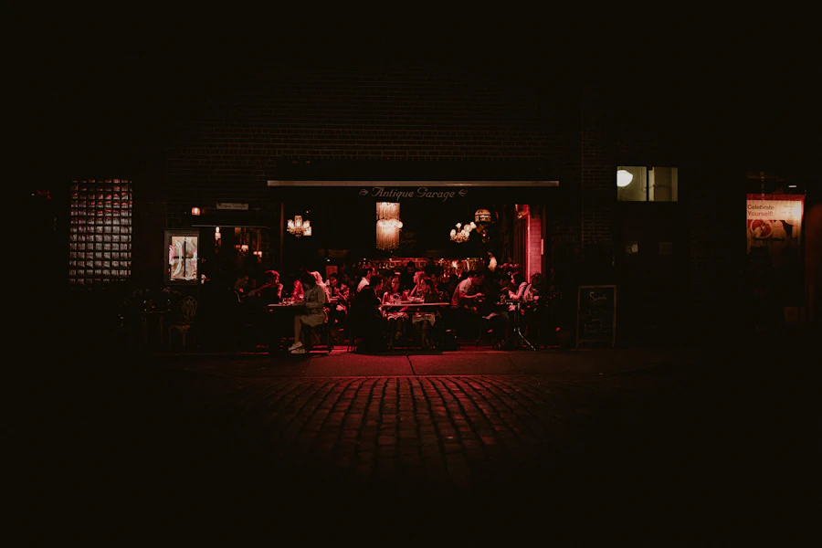 Restaurant patio glowing with red light, diners seated at tables at night